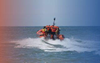 Orange lifeboat at sea conducting OPITO Boatman training