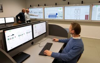 Instructor and delegates using the K-Sim Engine simulator, with multiple control panels and training monitors displaying ship engine room systems at Stream Marine Technical's Glasgow facility.