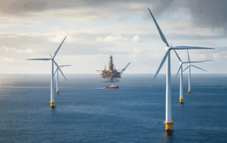 Offshore wind turbines and an oil platform in the same seascape with a support vessel passing through, symbolising the transition between oil and gas and renewable energy careers.