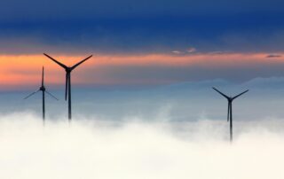 GWO Wind Turbine Training - clouds and mist crowing over ground level with wind turbines on orange and blue skyline