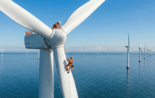 Two wind turbine technicians wearing safety gear carrying out blade maintenance on an offshore turbine, demonstrating the type of work supported by GWO training and wind energy careers in the UK.
