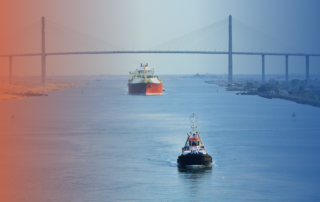 Cargo vessel and tugboat navigating a waterway under a bridge, representing IGF Code compliance and low-flashpoint fuel regulations in maritime operations